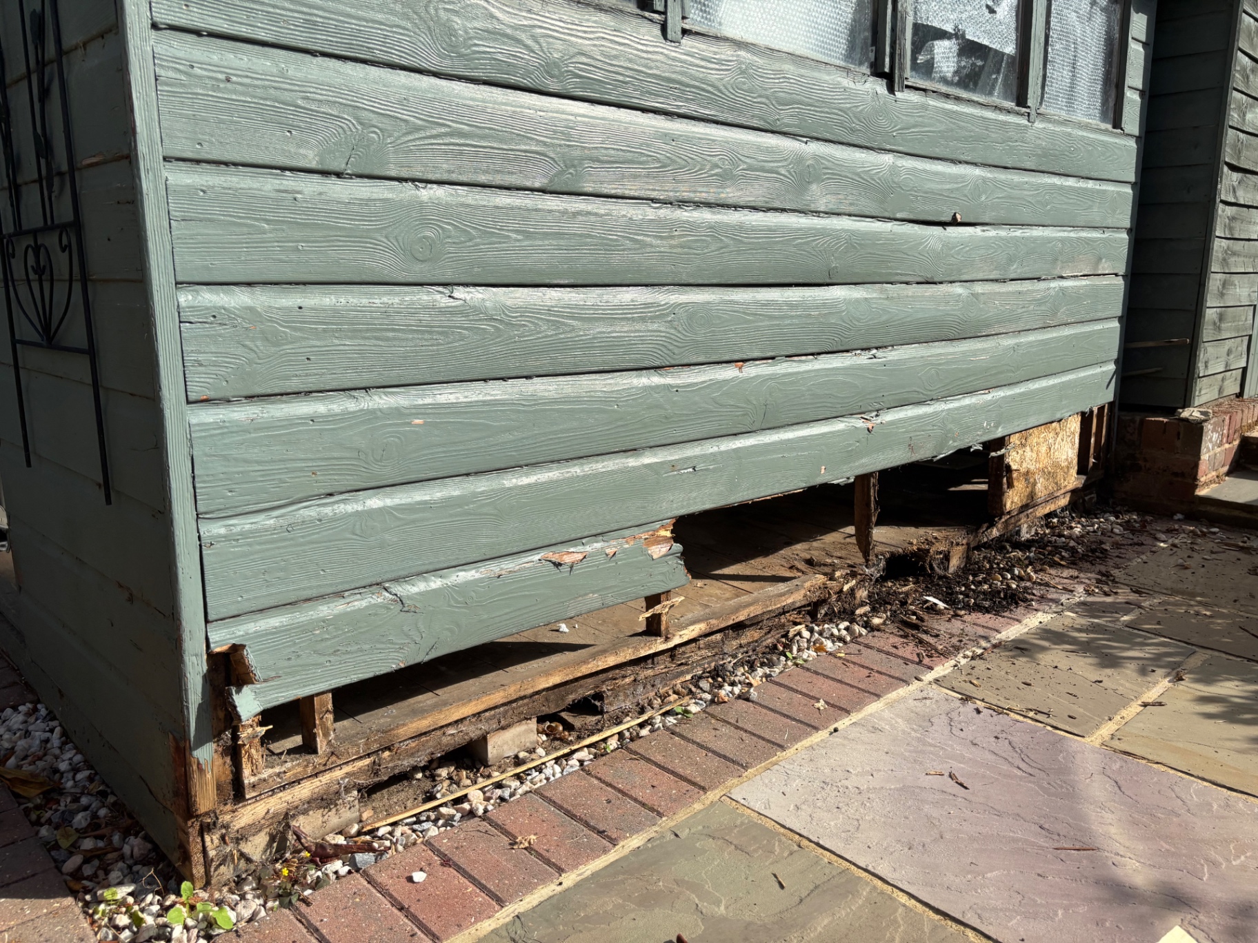 Rotted timber cladding and failed base removed from the garden room — before
